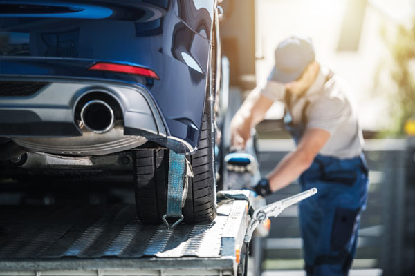 photo of an auto transport driver securing a vehicle to the carrier